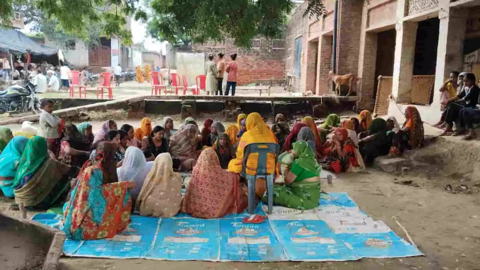 तस्वीर में दिख रही ग्रामीण महिलाएं खुले स्थान पर बिछी नीली शीट पर एक समूह में बैठी हैं। तस्वीर में दिख रही ग्रामीण महिलाएं खुले स्थान पर बिछी नीली शीट पर एक समूह में बैठी हैं।