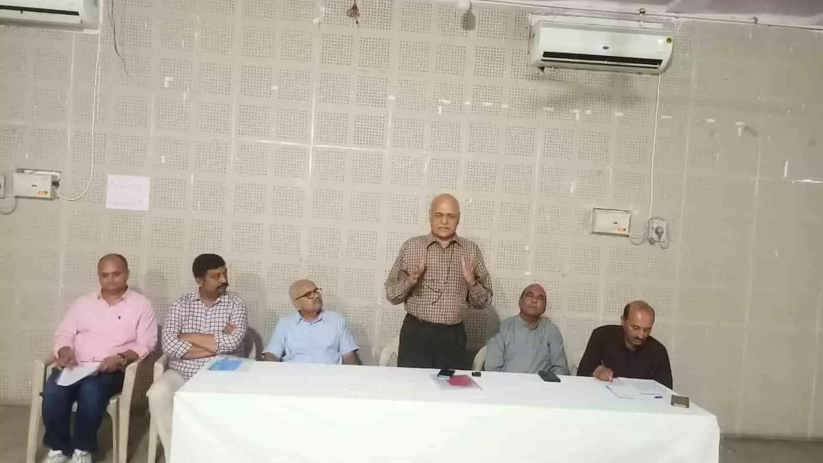 तस्वीर में दिख रही एक हॉल में टेबल पर बैठे लोग प्रेस कॉन्फ्रेंस को संबोधित कर रहे हैं। तस्वीर में दिख रही एक हॉल में टेबल पर बैठे लोग प्रेस कॉन्फ्रेंस को संबोधित कर रहे हैं।