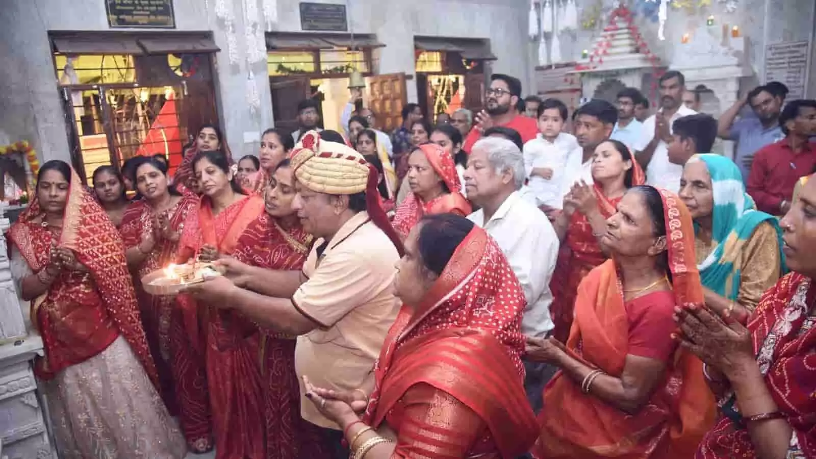 तस्वीर में मंदिर परिसर के अंदर पारंपरिक पोशाक में श्रद्धालु आरती और पूजा करते हुए दिखाई दे रहे हैं। तस्वीर में मंदिर परिसर के अंदर पारंपरिक पोशाक में श्रद्धालु आरती और पूजा करते हुए दिखाई दे रहे हैं।