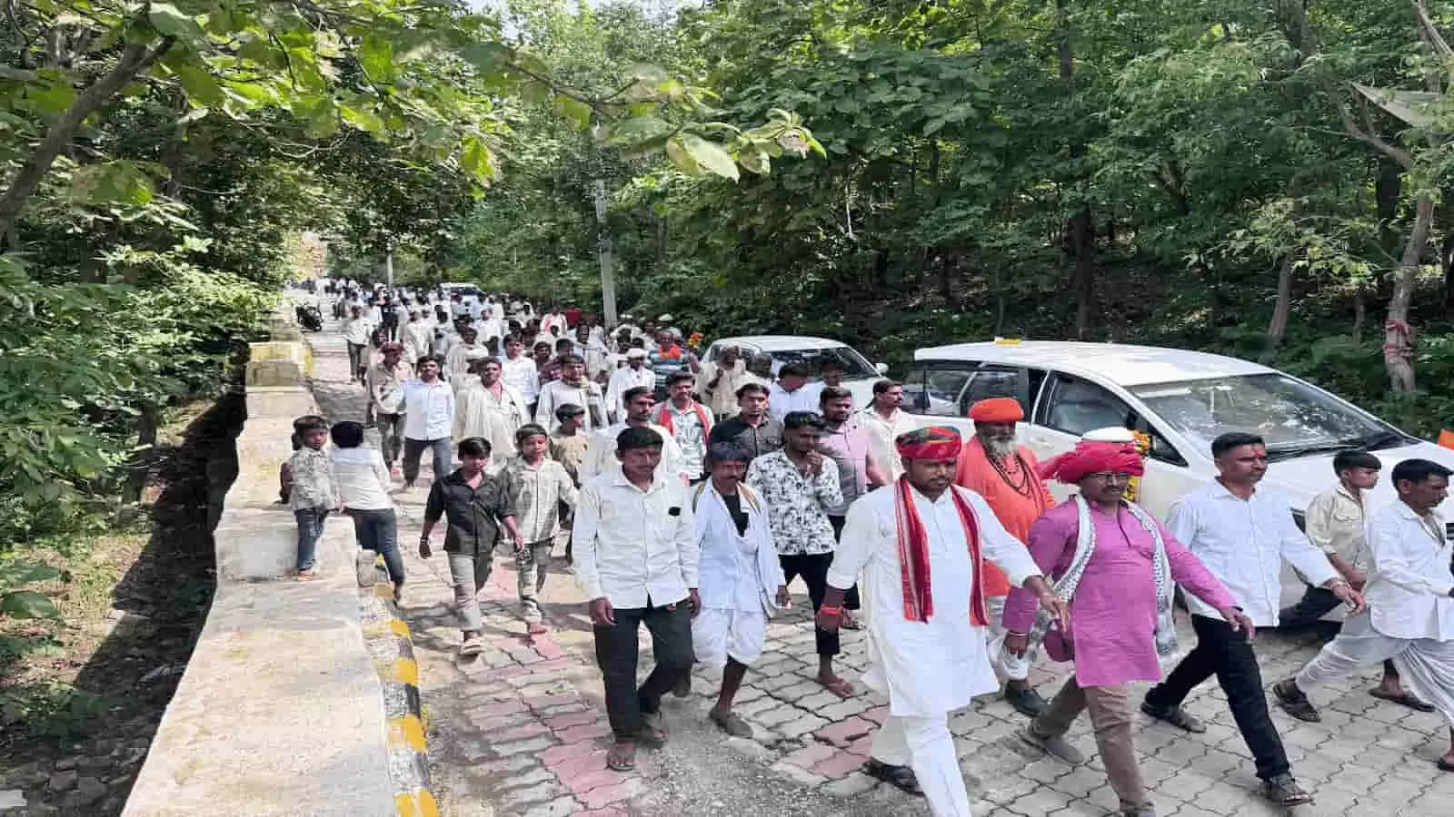 तस्वीर में पारंपरिक पोशाक पहने लोग और ग्रामीण लासाड़िया क्षेत्र में सड़क पर एक साथ चल रहे हैं। तस्वीर में पारंपरिक पोशाक पहने लोग और ग्रामीण लासाड़िया क्षेत्र में सड़क पर एक साथ चल रहे हैं।
