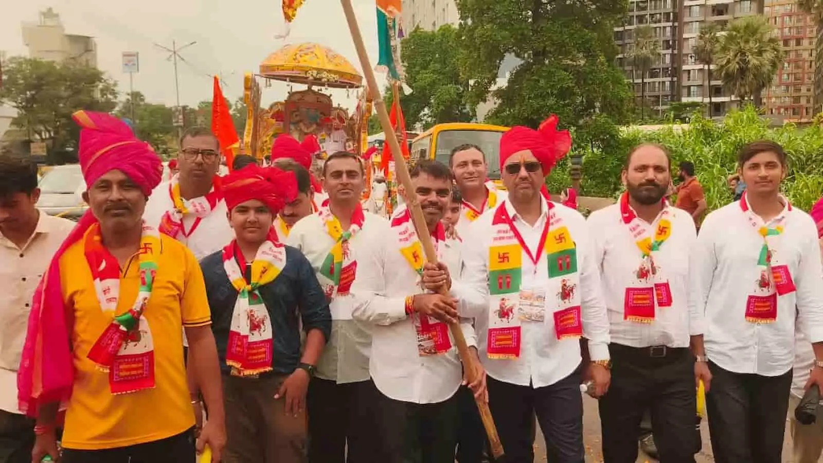 तस्वीर में पारंपरिक साफे और गले में पट्टिका पहने लोगों का समूह नालासोपारा में शोभायात्रा के दौरान सड़क पर चल रहा है तस्वीर में पारंपरिक साफे और गले में पट्टिका पहने लोगों का समूह नालासोपारा में शोभायात्रा के दौरान सड़क पर चल रहा है