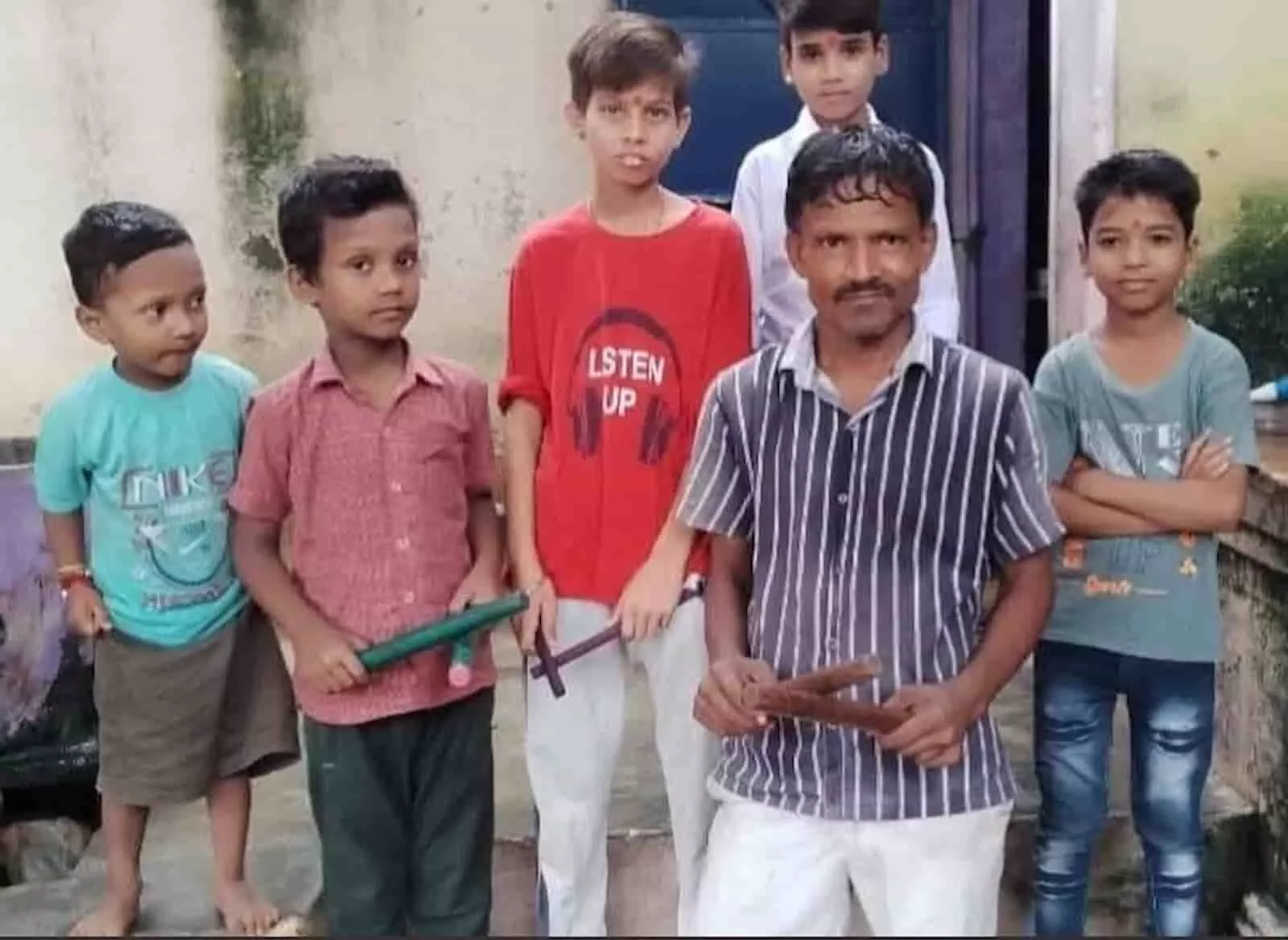 तस्वीर में बाएं से दाएं चार बच्चे और एक पुरुष हाथों में डंडे थामे खड़े नजर आ रहे हैं। तस्वीर में बाएं से दाएं चार बच्चे और एक पुरुष हाथों में डंडे थामे खड़े नजर आ रहे हैं।