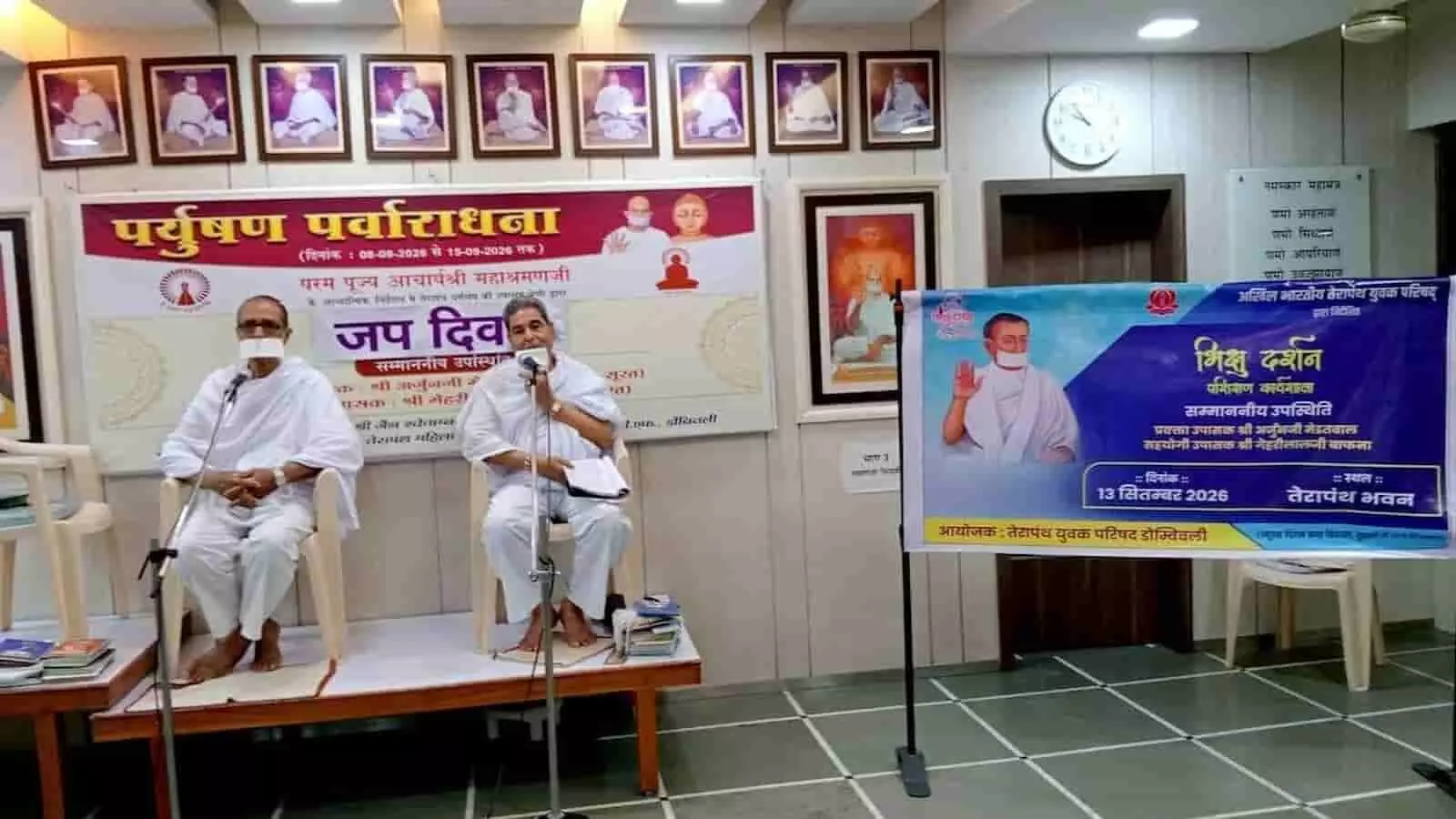 तस्वीर में एक हॉल में मंच की कुर्सियों पर बैठे दो श्वेत वस्त्रधारी वक्ता और दीवार पर लगे बैनर दिखाई दे रहे हैं। तस्वीर में एक हॉल में मंच की कुर्सियों पर बैठे दो श्वेत वस्त्रधारी वक्ता और दीवार पर लगे बैनर दिखाई दे रहे हैं।