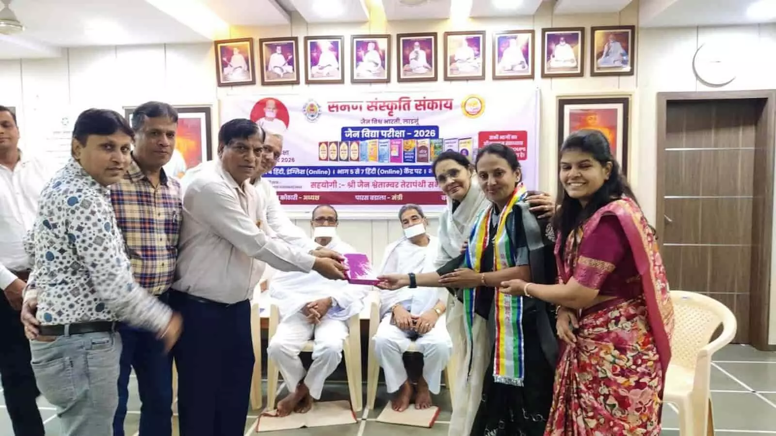 तस्वीर में बाएं से दाएं खड़े हुए कई लोग एक महिला को उपहार और प्रमाण पत्र सौंपते हुए दिखाई दे रहे हैं। तस्वीर में बाएं से दाएं खड़े हुए कई लोग एक महिला को उपहार और प्रमाण पत्र सौंपते हुए दिखाई दे रहे हैं।