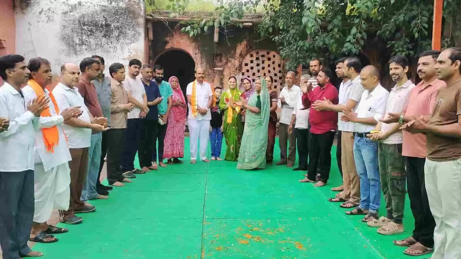 तस्वीर में मंदिर परिसर की हरी चटाई पर पुरुष और महिलाएं खड़े होकर ताली बजा रहे हैं। तस्वीर में मंदिर परिसर की हरी चटाई पर पुरुष और महिलाएं खड़े होकर ताली बजा रहे हैं।