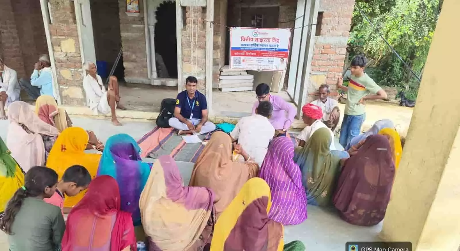तस्वीर में मंदिर परिसर में अधिकारियों के सामने बैठकर बैंकिंग योजनाओं की जानकारी लेते महिला और पुरुष ग्रामीण दिख रहे हैं। तस्वीर में मंदिर परिसर में अधिकारियों के सामने बैठकर बैंकिंग योजनाओं की जानकारी लेते महिला और पुरुष ग्रामीण दिख रहे हैं।
