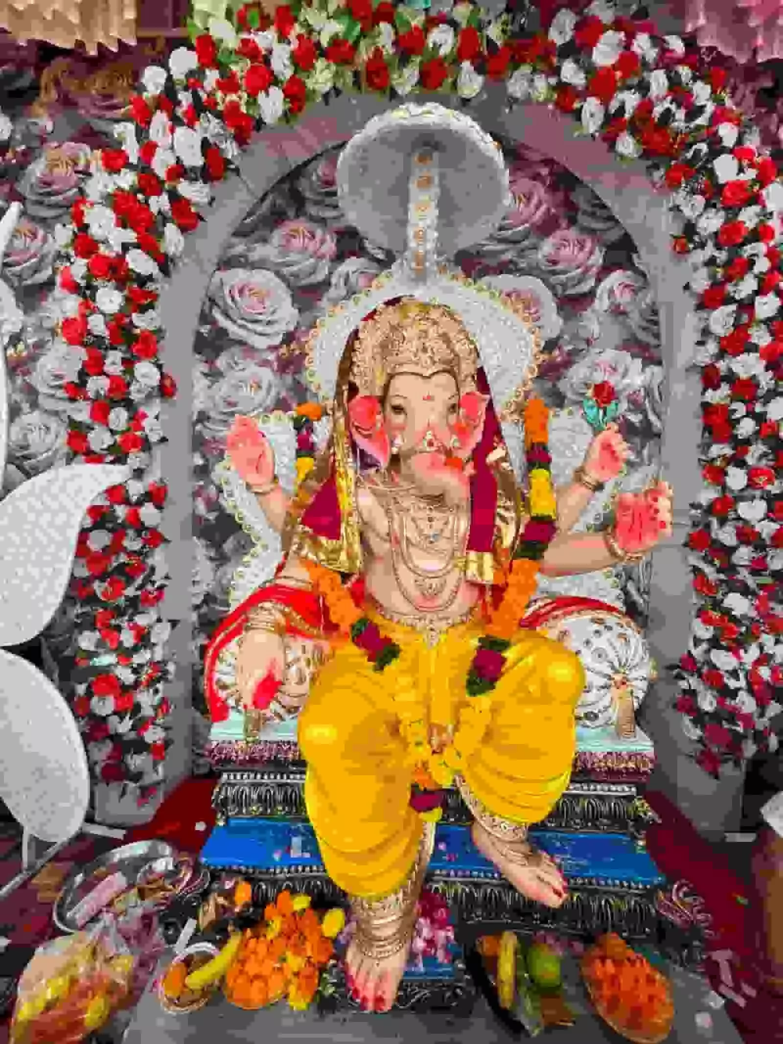 तस्वीर में फूलों से सजे पंडाल के भीतर पीले वस्त्रों में विराजमान भगवान गणेश की प्रतिमा दिख रही है। तस्वीर में फूलों से सजे पंडाल के भीतर पीले वस्त्रों में विराजमान भगवान गणेश की प्रतिमा दिख रही है।