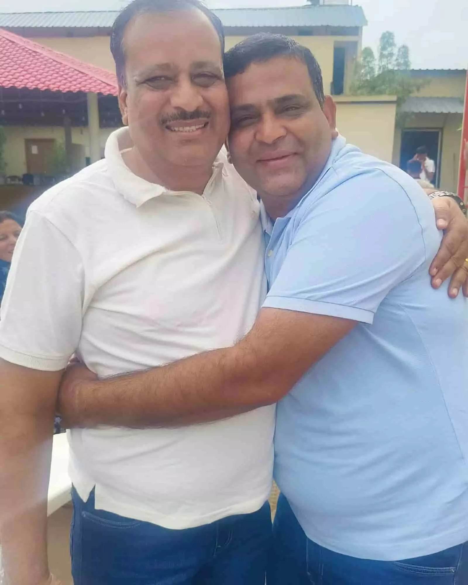 तस्वीर में दिख रहे दो लोग बाएं से दाएं खड़े होकर मुस्कुराते हुए आपस में गले मिल रहे हैं। तस्वीर में दिख रहे दो लोग बाएं से दाएं खड़े होकर मुस्कुराते हुए आपस में गले मिल रहे हैं।