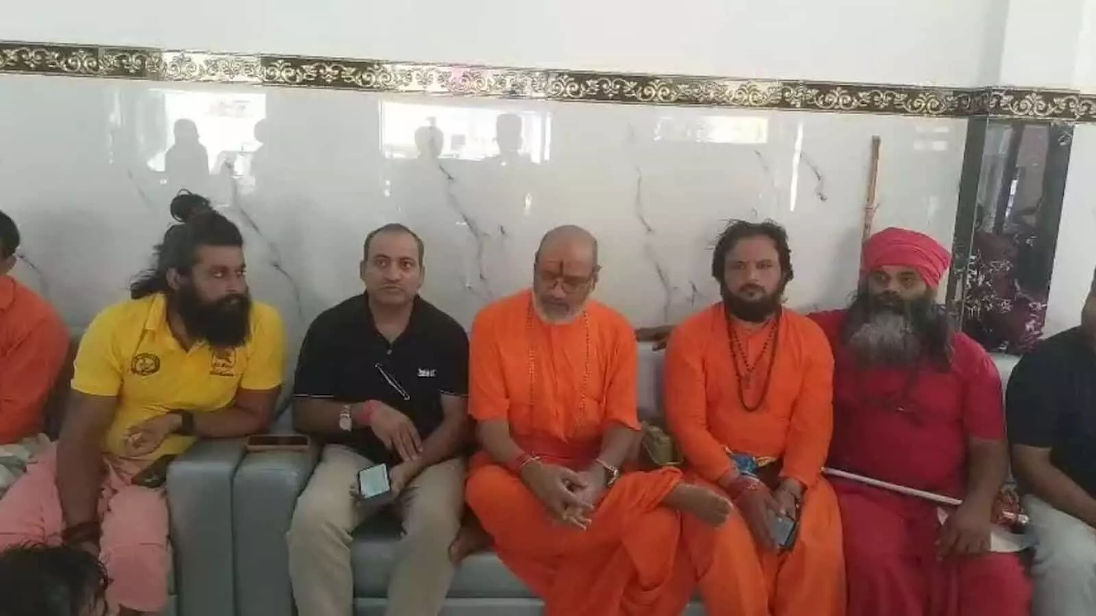 तस्वीर में बाएं से दाएं एक व्यक्ति, पीले वस्त्र पहने व्यक्ति, काले कपड़े पहने व्यक्ति, भगवा वस्त्र पहने यति नरसिंहानंद, और अन्य लोग सोफे पर बैठे दिखाई दे रहे हैं। तस्वीर में बाएं से दाएं एक व्यक्ति, पीले वस्त्र पहने व्यक्ति, काले कपड़े पहने व्यक्ति, भगवा वस्त्र पहने यति नरसिंहानंद, और अन्य लोग सोफे पर बैठे दिखाई दे रहे हैं।