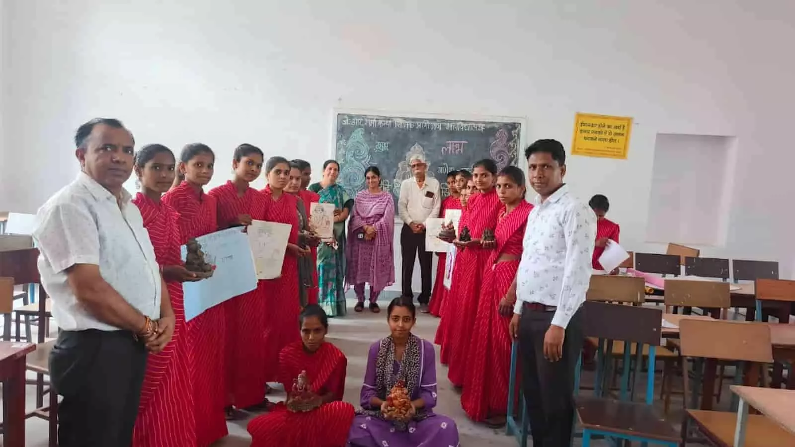 तस्वीर में लाल पोशाक पहनी छात्राएं और शिक्षक वर्ग कक्षा में हाथ में पोस्टर लिए खड़े हैं। तस्वीर में लाल पोशाक पहनी छात्राएं और शिक्षक वर्ग कक्षा में हाथ में पोस्टर लिए खड़े हैं।