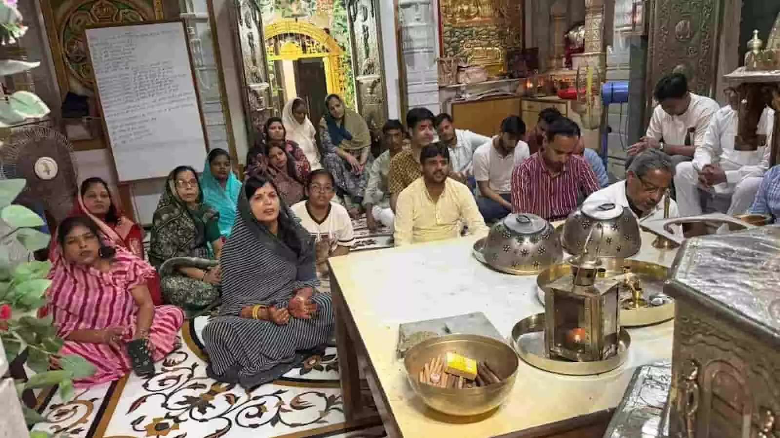 तस्वीर में दिख रही महिलाएं और पुरुष मंदिर में पूजा की सामग्री के सामने बैठकर अनुष्ठान कर रहे हैं। तस्वीर में दिख रही महिलाएं और पुरुष मंदिर में पूजा की सामग्री के सामने बैठकर अनुष्ठान कर रहे हैं।