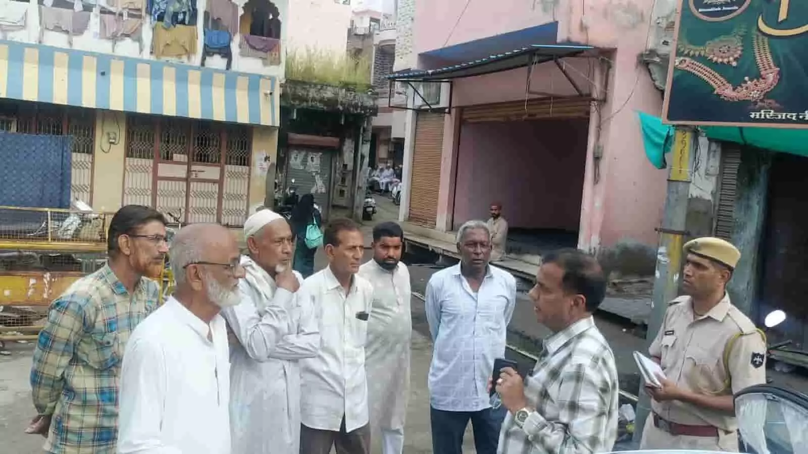 तस्वीर में दिख रही बाजार की सड़क पर अधिकारी स्थानीय लोगों से चर्चा कर रहे हैं। तस्वीर में दिख रही बाजार की सड़क पर अधिकारी स्थानीय लोगों से चर्चा कर रहे हैं।