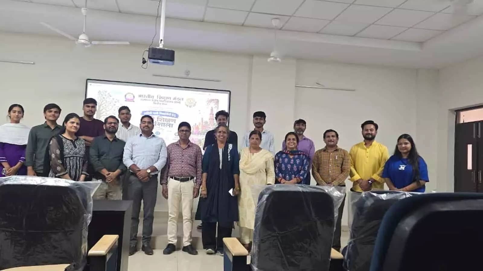 तस्वीर में विश्वविद्यालय के एक हॉल में स्क्रीन के आगे शिक्षक और विद्यार्थी समूह में खड़े हैं। तस्वीर में विश्वविद्यालय के एक हॉल में स्क्रीन के आगे शिक्षक और विद्यार्थी समूह में खड़े हैं।