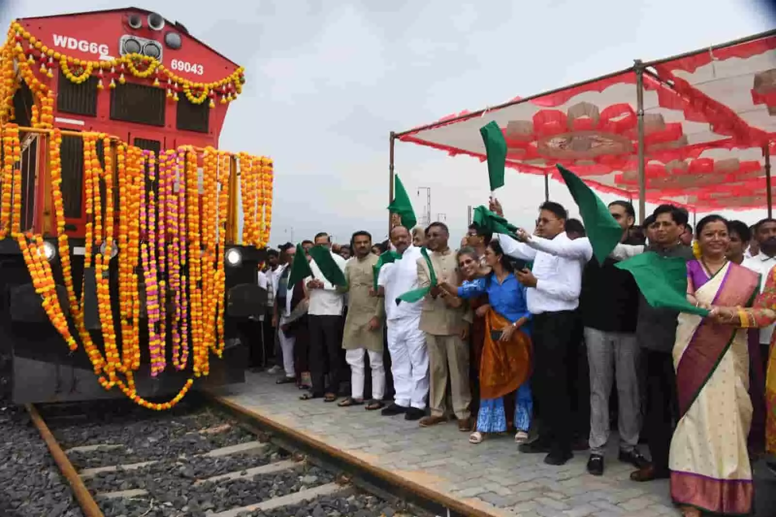 रेलवे पटरी के पास खड़े जनप्रतिनिधि और अधिकारी फूलों से सजी ट्रेन को हरी झंडी दिखा रहे हैं। रेलवे पटरी के पास खड़े जनप्रतिनिधि और अधिकारी फूलों से सजी ट्रेन को हरी झंडी दिखा रहे हैं।