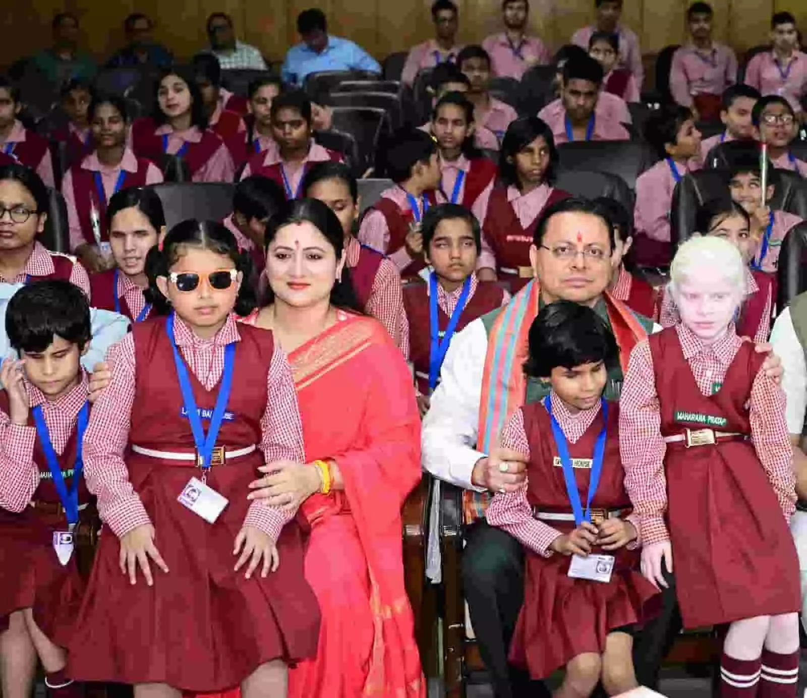 तस्वीर में बाईं तरफ गीता धामी और दाईं तरफ पुष्कर सिंह धामी स्कूली बच्चों के साथ बैठे हैं। तस्वीर में बाईं तरफ गीता धामी और दाईं तरफ पुष्कर सिंह धामी स्कूली बच्चों के साथ बैठे हैं।