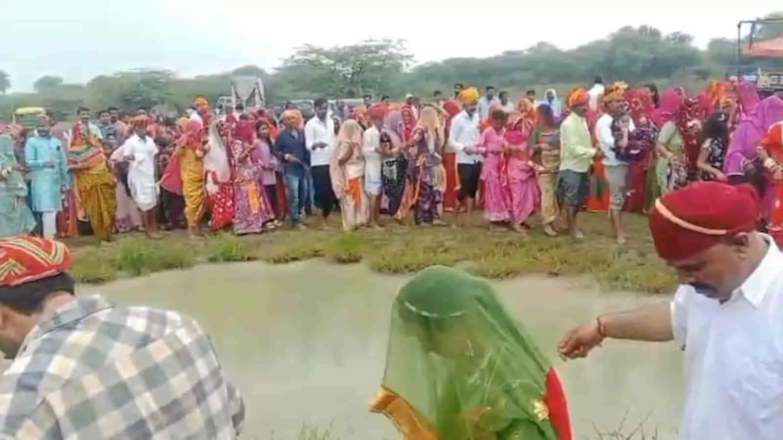 तस्वीर में दिख रही महिलाएं और पुरुष जलाशय के समीप खड़े होकर धार्मिक अनुष्ठान में भाग ले रहे हैं। तस्वीर में दिख रही महिलाएं और पुरुष जलाशय के समीप खड़े होकर धार्मिक अनुष्ठान में भाग ले रहे हैं।