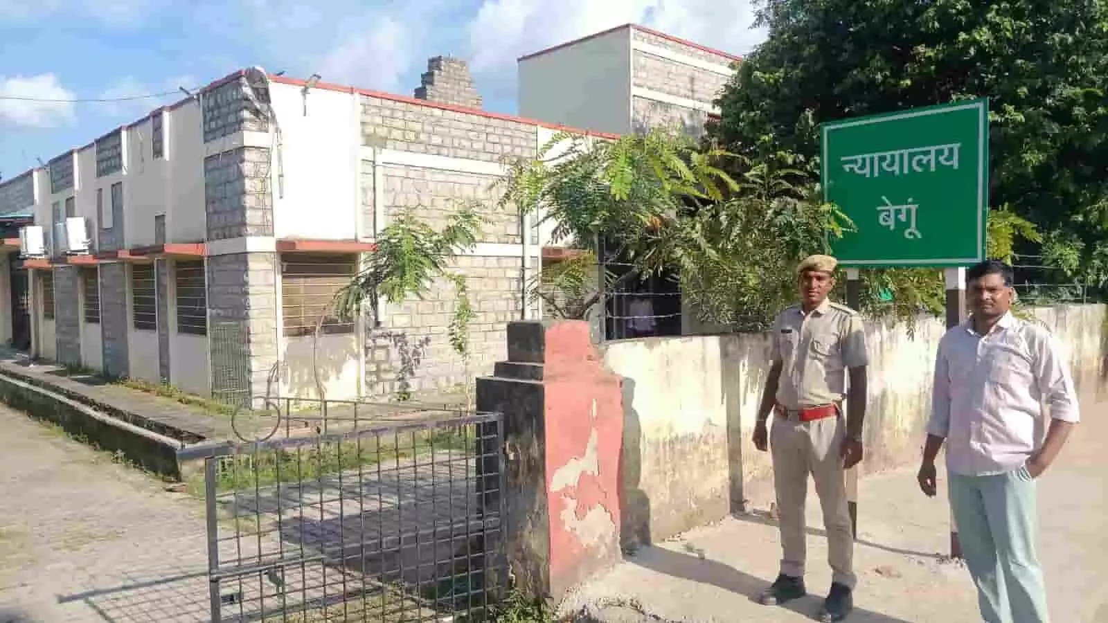 तस्वीर में बाईं ओर एक पुलिसकर्मी और दाईं ओर एक व्यक्ति बेगूं न्यायालय के बोर्ड के पास खड़े हैं। तस्वीर में बाईं ओर एक पुलिसकर्मी और दाईं ओर एक व्यक्ति बेगूं न्यायालय के बोर्ड के पास खड़े हैं।