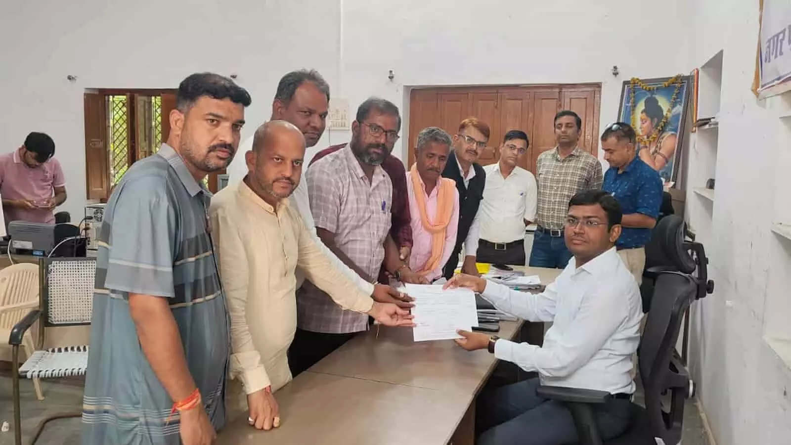 तस्वीर में दिख रही कार्यालय की मेज पर अधिकारी को पर्चा थमाते लोग मौजूद हैं। तस्वीर में दिख रही कार्यालय की मेज पर अधिकारी को पर्चा थमाते लोग मौजूद हैं।