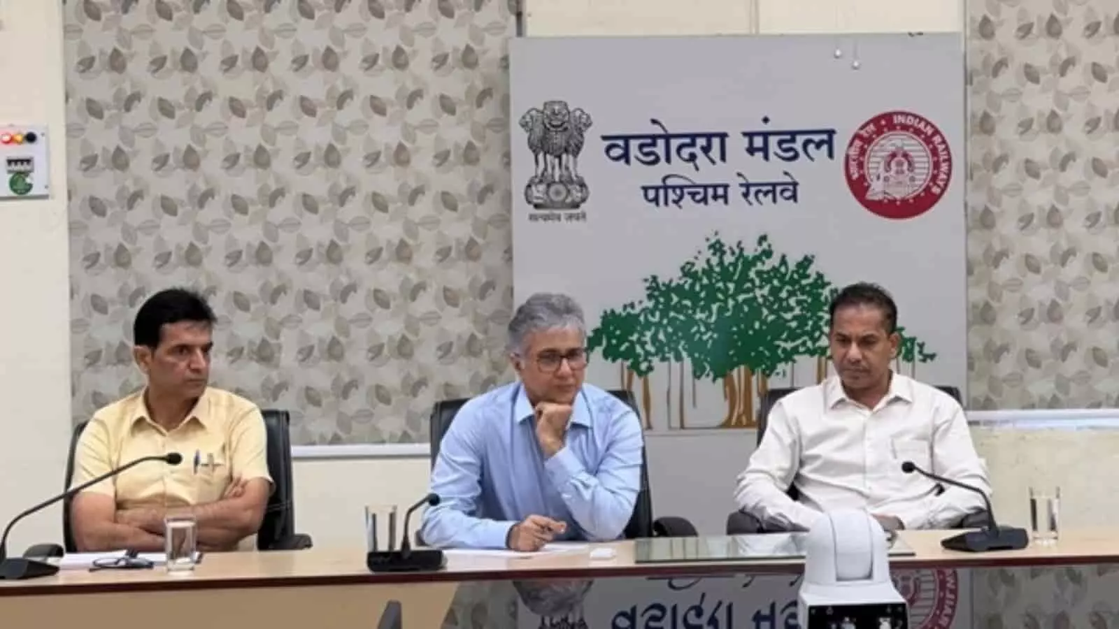 तस्वीर में बाएं से दाएं तीन पुरुष अधिकारी टेबल के पीछे बैठकर बैठक में भाग ले रहे हैं। तस्वीर में बाएं से दाएं तीन पुरुष अधिकारी टेबल के पीछे बैठकर बैठक में भाग ले रहे हैं।