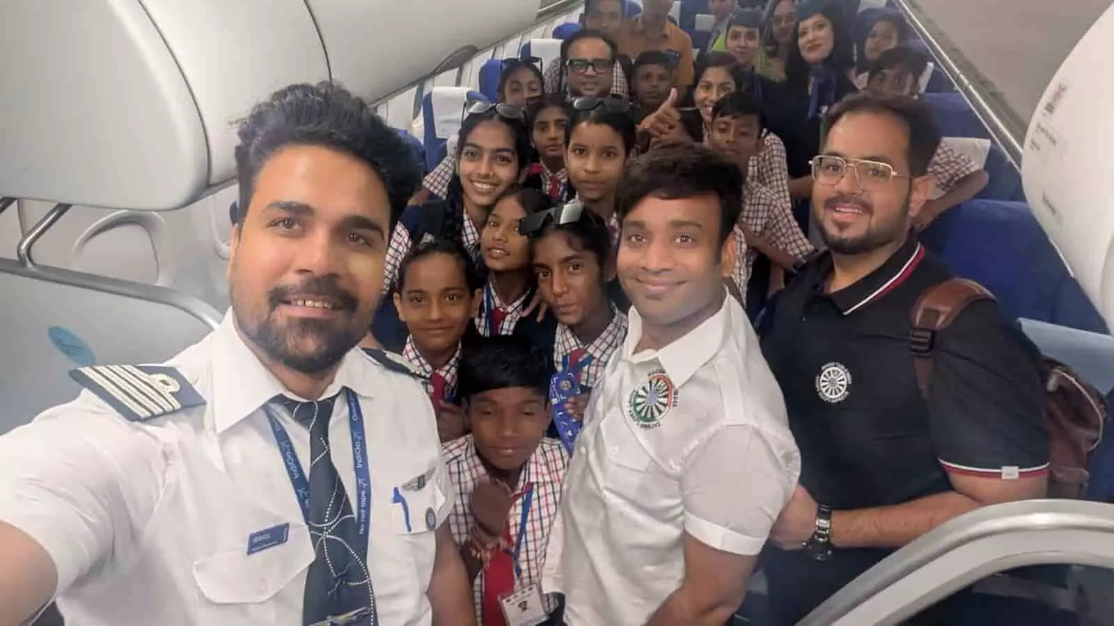 तस्वीर में दिख रही हवाई जहाज की केबिन में यूनिफॉर्म पहने स्कूली बच्चे और अन्य लोग मुस्कराते हुए सेल्फी खिंचवा रहे हैं। तस्वीर में दिख रही हवाई जहाज की केबिन में यूनिफॉर्म पहने स्कूली बच्चे और अन्य लोग मुस्कराते हुए सेल्फी खिंचवा रहे हैं।