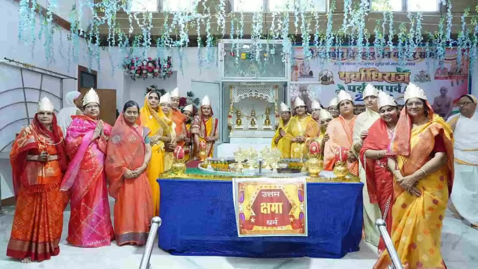 पारंपरिक साड़ियों और मुकुट में महिलाएं हॉल में उत्तम क्षमा धर्म के बैनर के पास खड़ी हैं। पारंपरिक साड़ियों और मुकुट में महिलाएं हॉल में उत्तम क्षमा धर्म के बैनर के पास खड़ी हैं।