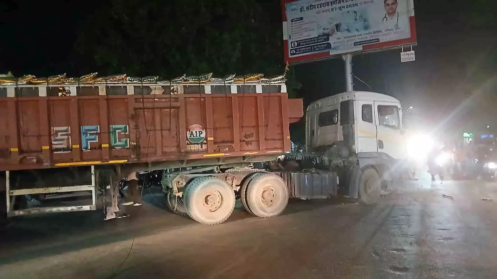 तस्वीर में दिख रही सड़क पर बोरियों से भरा ट्रोला बीचों-बीच खड़ा है और पृष्ठभूमि में होर्डिंग बोर्ड लगा है। तस्वीर में दिख रही सड़क पर बोरियों से भरा ट्रोला बीचों-बीच खड़ा है और पृष्ठभूमि में होर्डिंग बोर्ड लगा है।