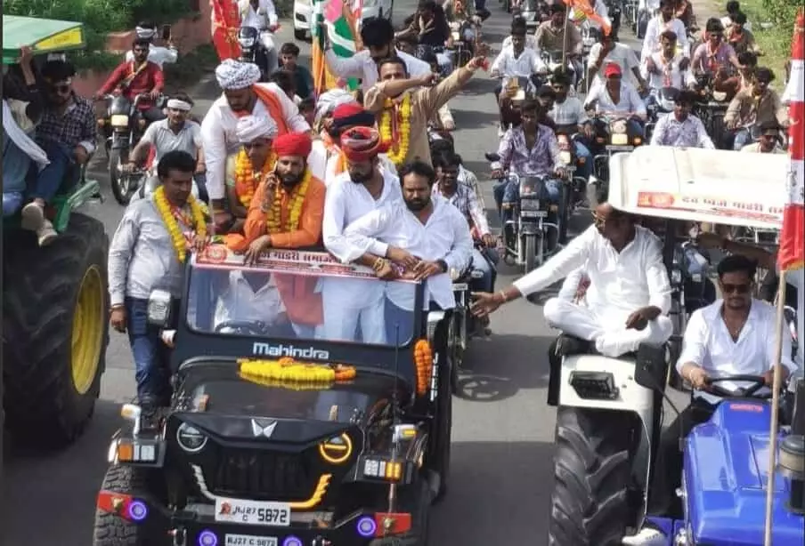 तस्वीर में सड़क पर वाहनों और मोटरसाइकिलों के काफिले के साथ आगे बढ़ रही शोभायात्रा में लोग झंडे थामे और गाड़ियों पर सवार दिखाई दे रहे हैं। तस्वीर में सड़क पर वाहनों और मोटरसाइकिलों के काफिले के साथ आगे बढ़ रही शोभायात्रा में लोग झंडे थामे और गाड़ियों पर सवार दिखाई दे रहे हैं।