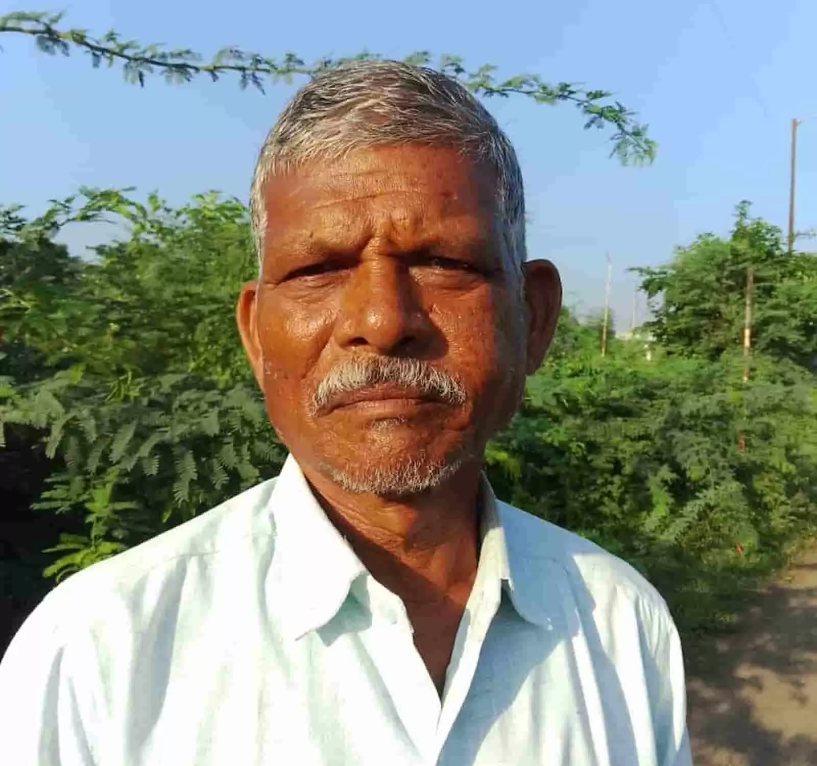 तस्वीर में दिख रहे एक वरिष्ठ व्यक्ति खुले क्षेत्र में सीधे कैमरे की ओर देख रहे हैं। तस्वीर में दिख रहे एक वरिष्ठ व्यक्ति खुले क्षेत्र में सीधे कैमरे की ओर देख रहे हैं।