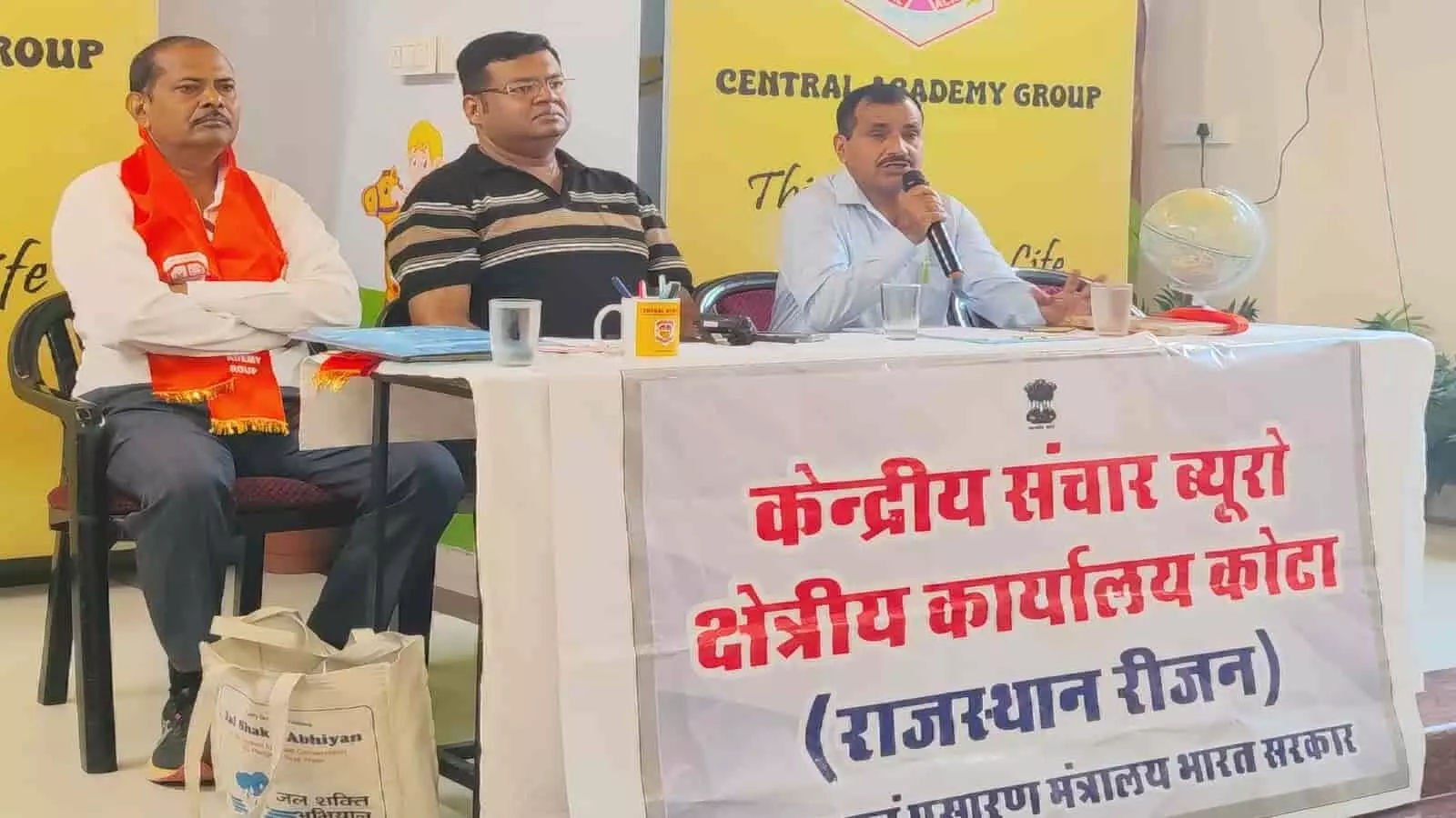 तस्वीर में बाएं से दाएं तीन व्यक्ति मंच पर बैठे हैं, जिनमें से एक व्यक्ति माइक में बोल रहा है और सामने केंद्रीय संचार ब्यूरो का बैनर लगा है। तस्वीर में बाएं से दाएं तीन व्यक्ति मंच पर बैठे हैं, जिनमें से एक व्यक्ति माइक में बोल रहा है और सामने केंद्रीय संचार ब्यूरो का बैनर लगा है।