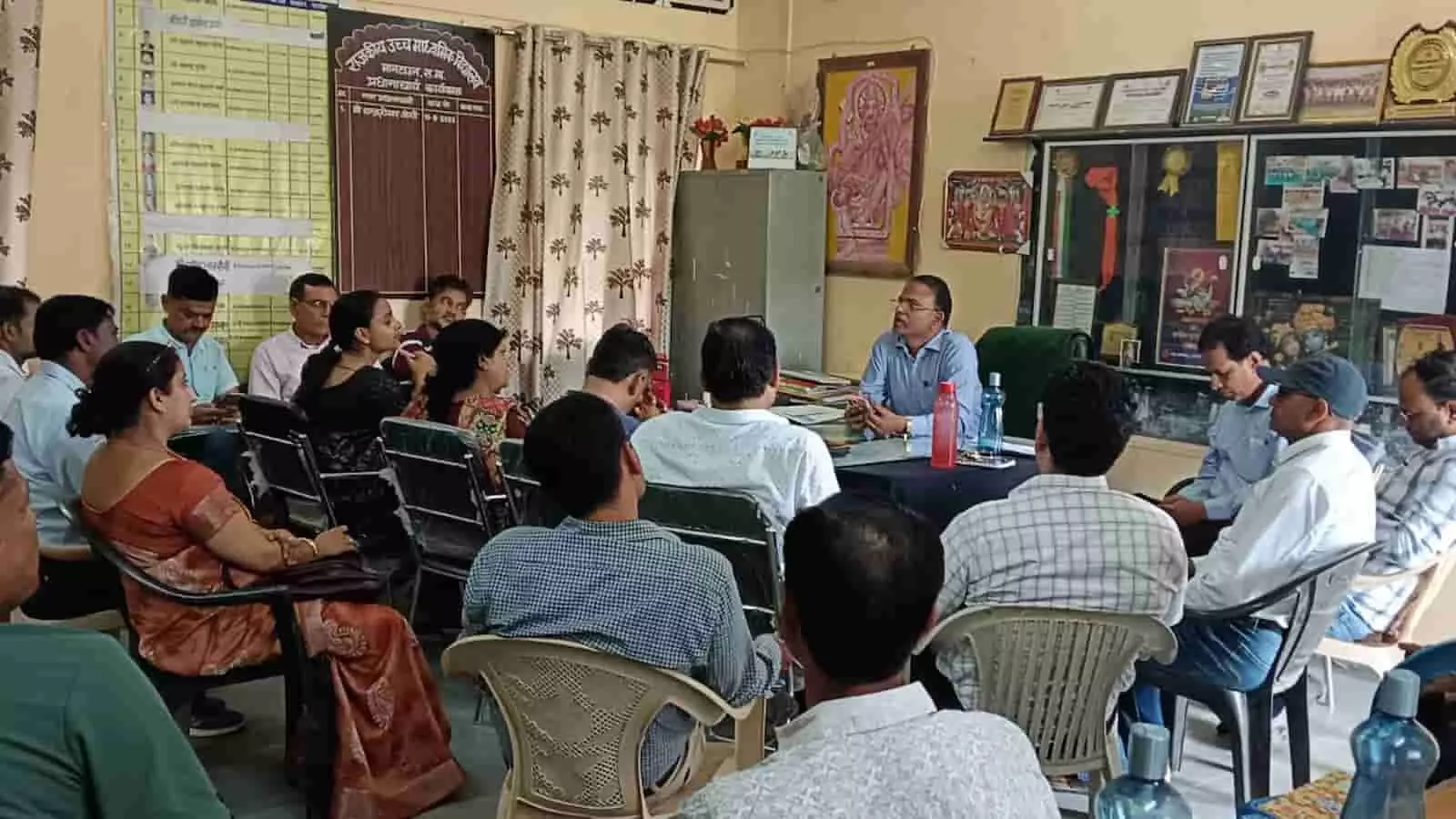 तस्वीर में एक कमरे में कुर्सियों पर बैठे अधिकारी और शिक्षक बैठक के दौरान चर्चा कर रहे हैं। तस्वीर में एक कमरे में कुर्सियों पर बैठे अधिकारी और शिक्षक बैठक के दौरान चर्चा कर रहे हैं।