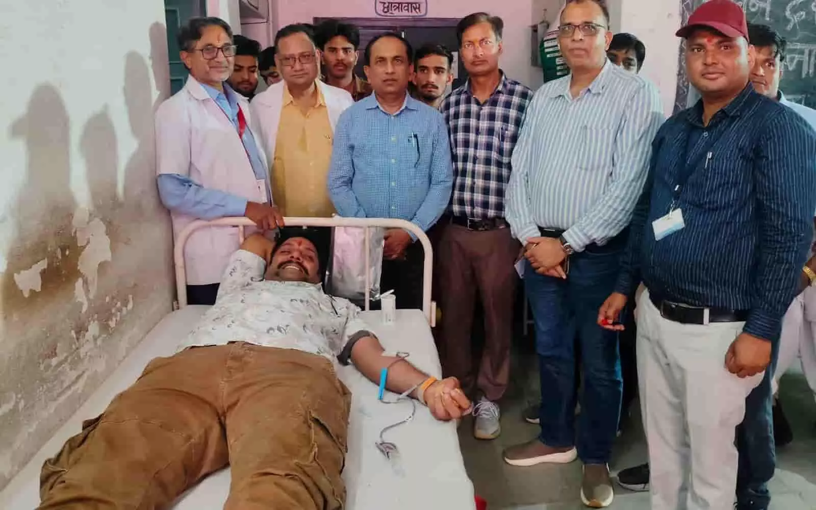 तस्वीर में दिख रहा व्यक्ति अस्पताल के बेड पर लेटकर रक्तदान कर रहा है और स्वास्थ्य कर्मी पास खड़े हैं। तस्वीर में दिख रहा व्यक्ति अस्पताल के बेड पर लेटकर रक्तदान कर रहा है और स्वास्थ्य कर्मी पास खड़े हैं।