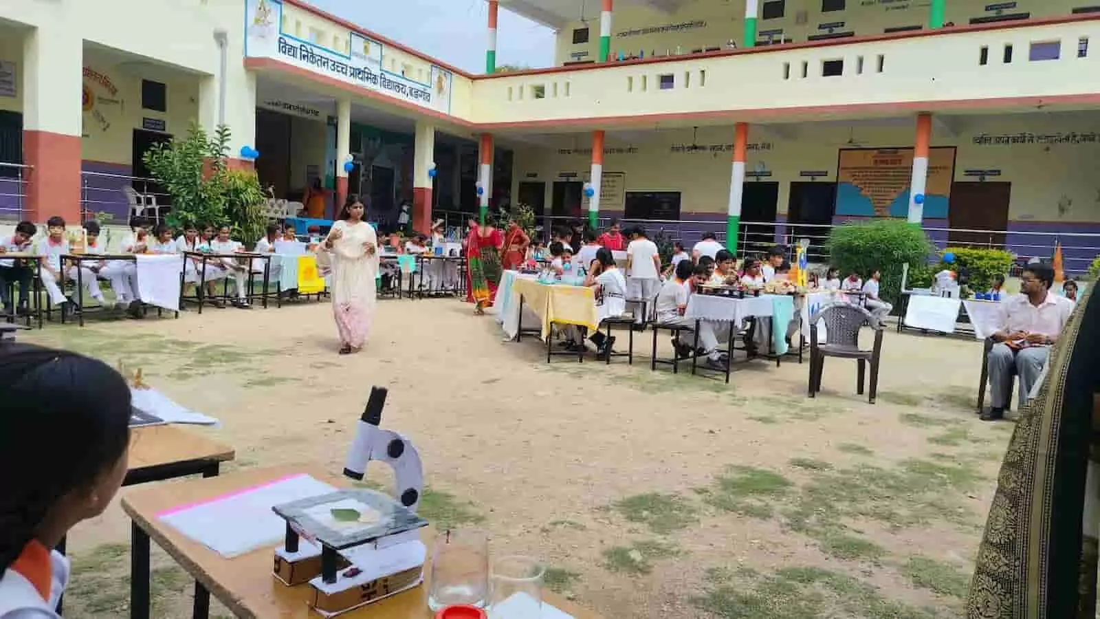 तस्वीर में दिख रही खुले प्रांगण की मेजों पर छात्र विज्ञान के मॉडल और प्रयोग प्रदर्शित कर रहे हैं। तस्वीर में दिख रही खुले प्रांगण की मेजों पर छात्र विज्ञान के मॉडल और प्रयोग प्रदर्शित कर रहे हैं।