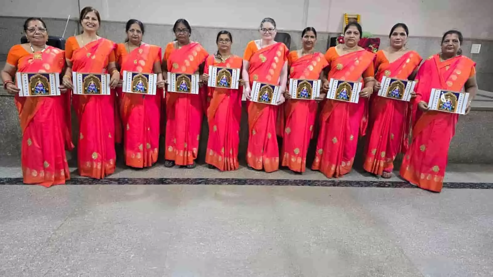 तस्वीर में बाएं से दाएं एक जैसी लाल और नारंगी साड़ियां पहने दस महिलाएं हाथ में महाराजा अग्रसेन की तस्वीर थामकर खड़ी हैं। तस्वीर में बाएं से दाएं एक जैसी लाल और नारंगी साड़ियां पहने दस महिलाएं हाथ में महाराजा अग्रसेन की तस्वीर थामकर खड़ी हैं।