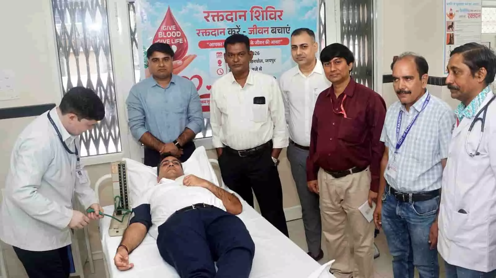 तस्वीर में अस्पताल के बेड पर एक व्यक्ति लेटा है और उसके पास कई अधिकारी खड़े हैं। तस्वीर में अस्पताल के बेड पर एक व्यक्ति लेटा है और उसके पास कई अधिकारी खड़े हैं।