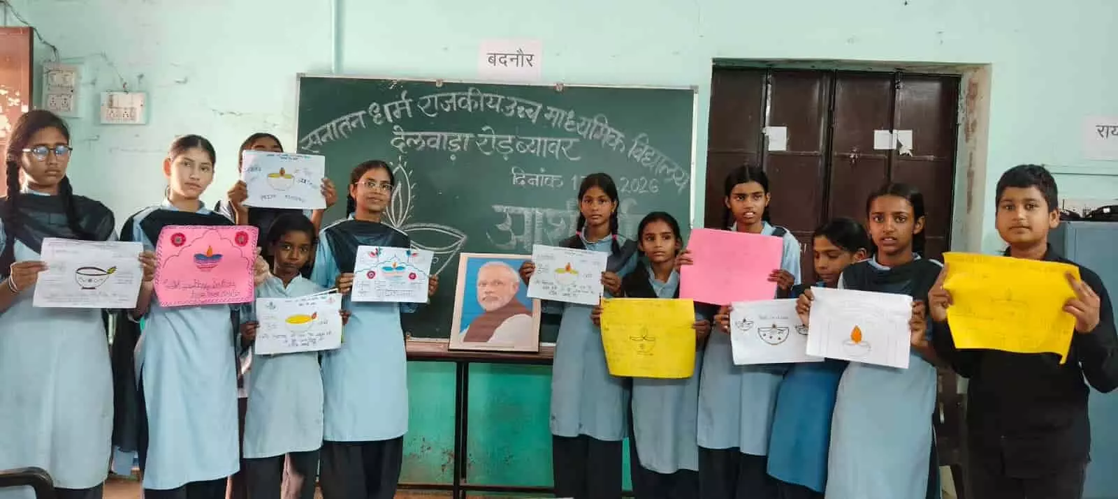 तस्वीर में बाएं से दाएं स्कूल की यूनिफॉर्म पहने कई विद्यार्थी अपने हाथों में पेंटिंग और चित्र थामकर खड़े हैं, और उनके पीछे ब्लैकबोर्ड पर विद्यालय का नाम लिखा हुआ है। तस्वीर में बाएं से दाएं स्कूल की यूनिफॉर्म पहने कई विद्यार्थी अपने हाथों में पेंटिंग और चित्र थामकर खड़े हैं, और उनके पीछे ब्लैकबोर्ड पर विद्यालय का नाम लिखा हुआ है।
