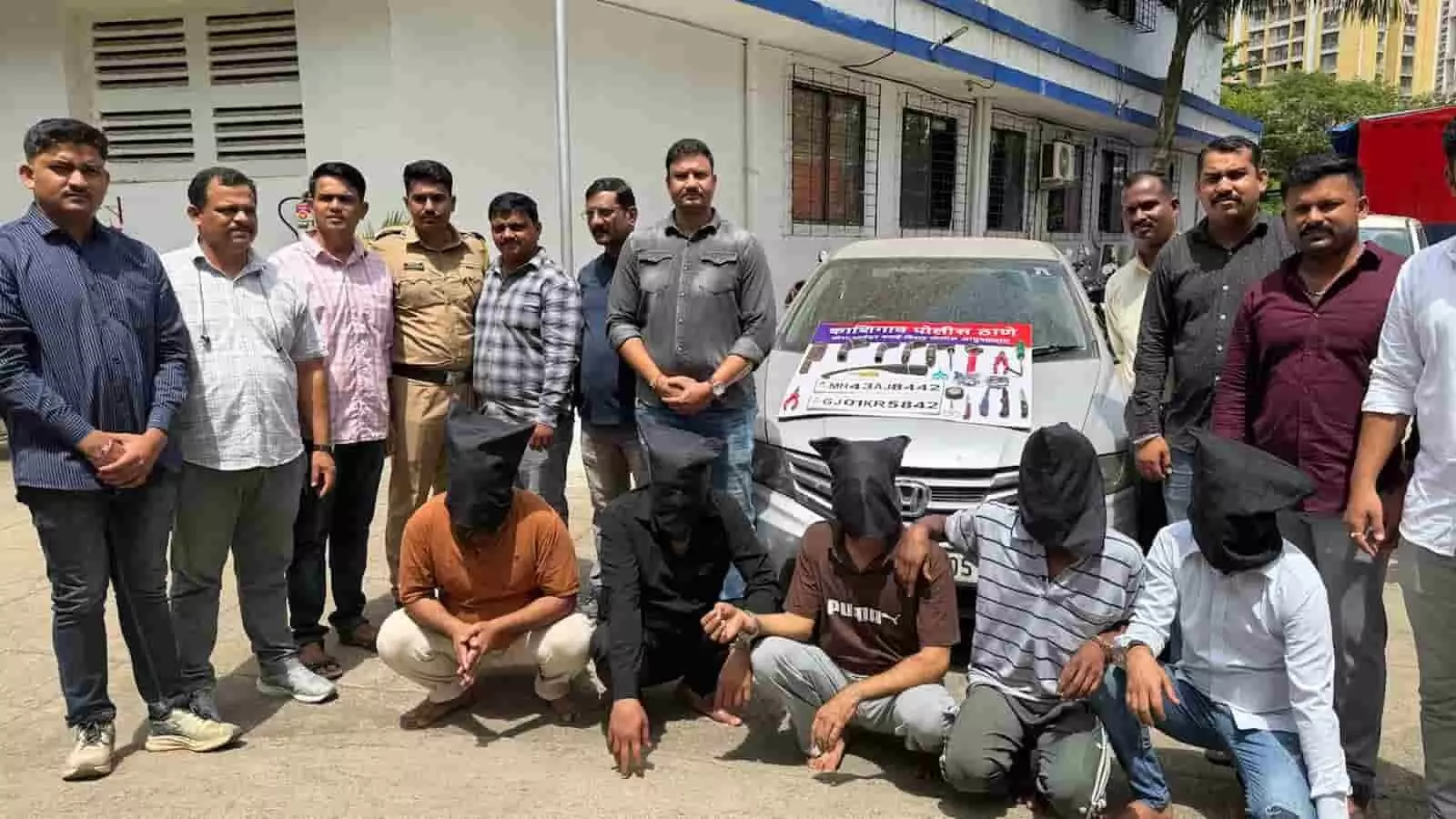 तस्वीर में बाएं से दाएं खड़े पुलिसकर्मियों के आगे सिर ढंके हुए बैठे पांचों आरोपी और पीछे एक कार दिखाई दे रही है। तस्वीर में बाएं से दाएं खड़े पुलिसकर्मियों के आगे सिर ढंके हुए बैठे पांचों आरोपी और पीछे एक कार दिखाई दे रही है।