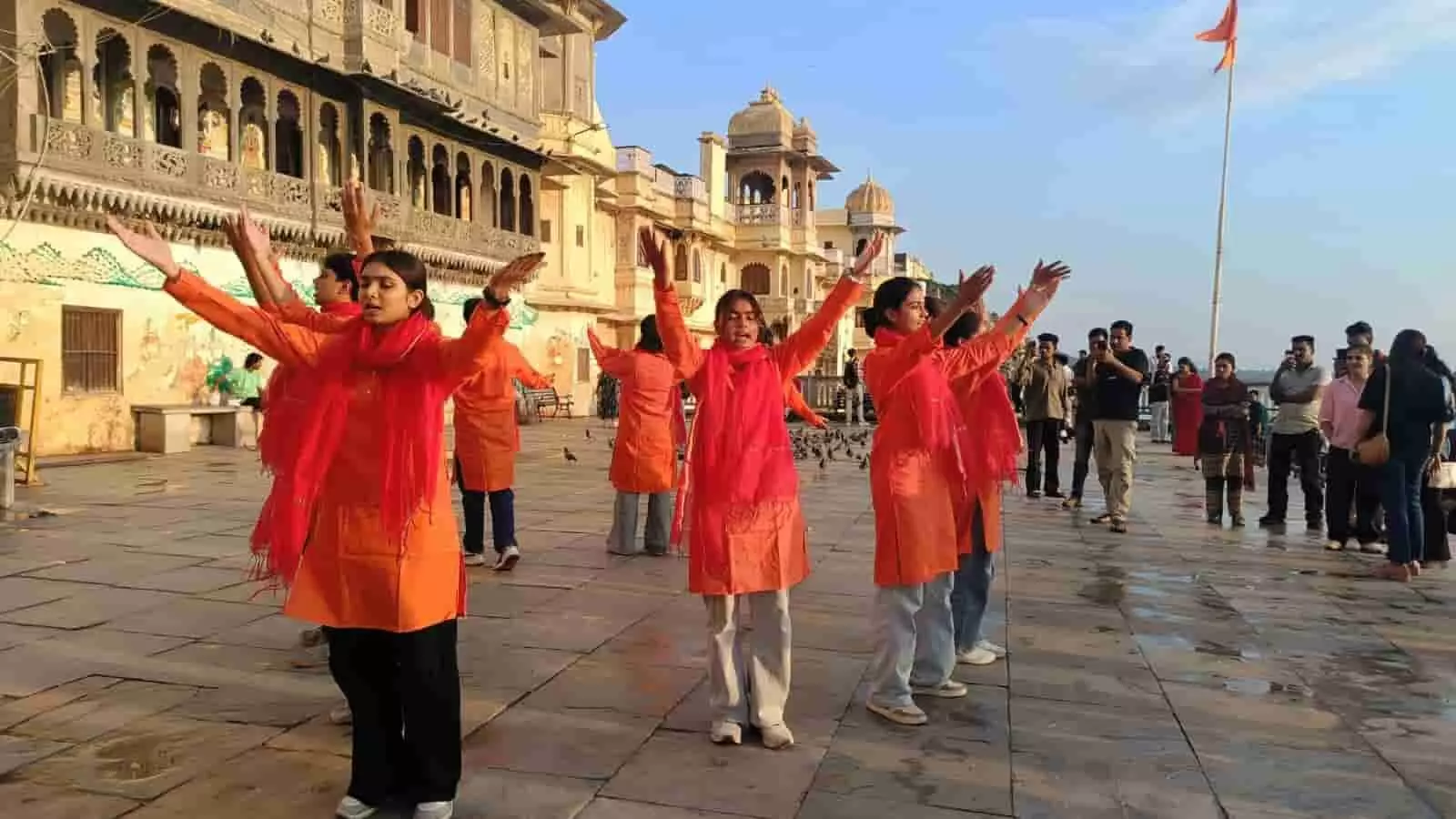 तस्वीर में पारंपरिक परिधानों में सजी युवतियां उदयपुर के गणगौर घाट पर खुले आसमान के नीचे नुक्कड़ नाटक का प्रदर्शन कर रही हैं, जिन्हें देखने के लिए दर्शक भी खड़े हैं। तस्वीर में पारंपरिक परिधानों में सजी युवतियां उदयपुर के गणगौर घाट पर खुले आसमान के नीचे नुक्कड़ नाटक का प्रदर्शन कर रही हैं, जिन्हें देखने के लिए दर्शक भी खड़े हैं।