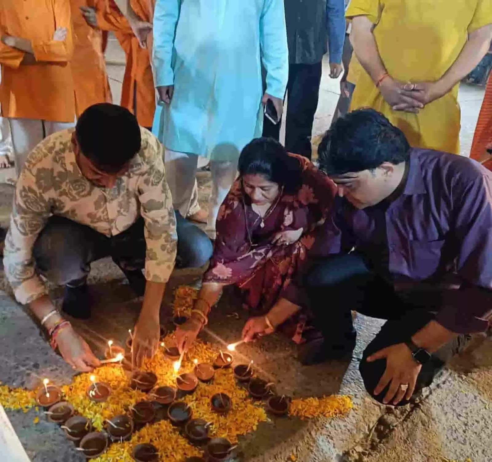 तस्वीर में दिख रही तीन हस्तियां जमीन पर फूलों के बीच रखे मिट्टी के दीपक प्रज्ज्वलित कर रही हैं। तस्वीर में दिख रही तीन हस्तियां जमीन पर फूलों के बीच रखे मिट्टी के दीपक प्रज्ज्वलित कर रही हैं।