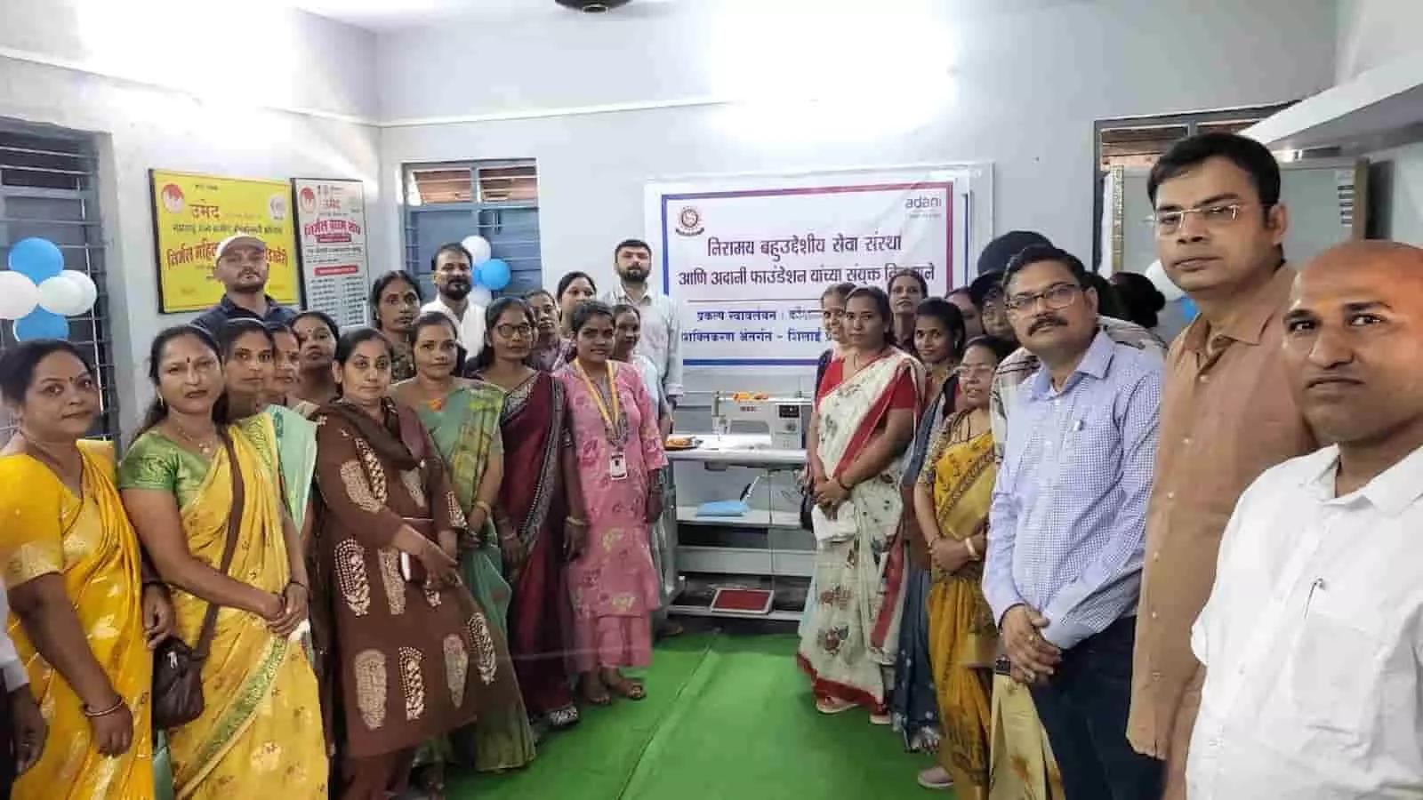तस्वीर में दिख रही महिलाएं और पुरुष कमरे में बैनर के सामने एक साथ खड़े हैं। तस्वीर में दिख रही महिलाएं और पुरुष कमरे में बैनर के सामने एक साथ खड़े हैं।
