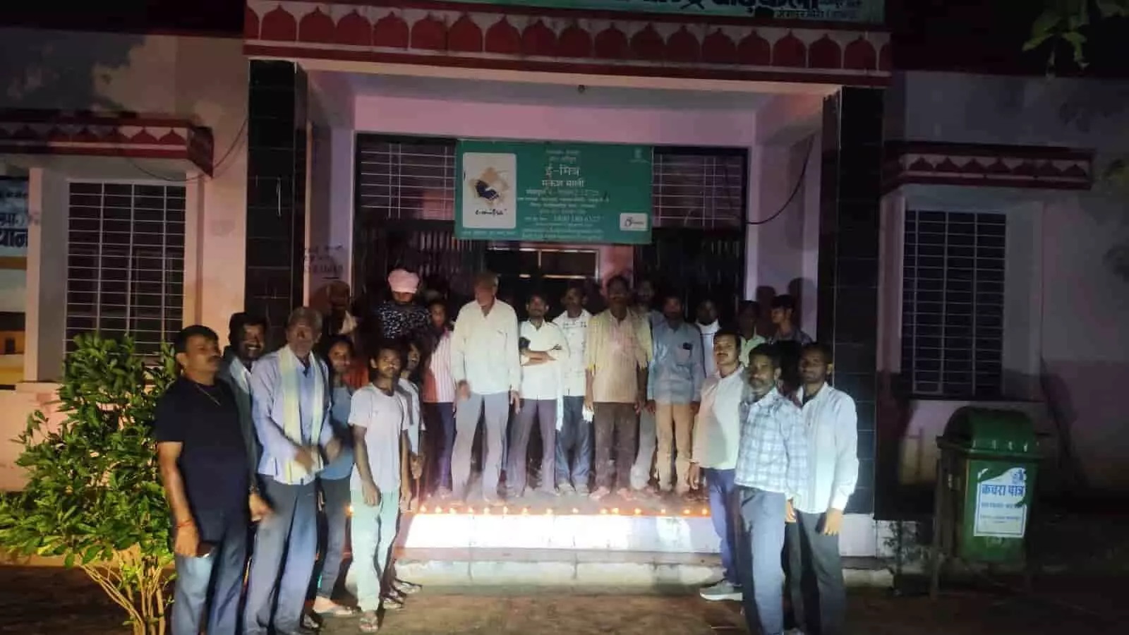 तस्वीर में दिख रही इमारत के बाहर स्थानीय निवासी रात के समय एक साथ खड़े हैं। तस्वीर में दिख रही इमारत के बाहर स्थानीय निवासी रात के समय एक साथ खड़े हैं।