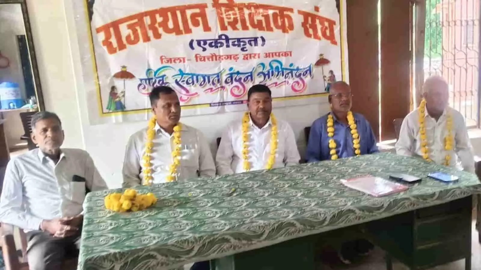 तस्वीर में दिख रही मेज के पीछे पांच पुरुष एक साथ बैठे हुए नजर आ रहे हैं। तस्वीर में दिख रही मेज के पीछे पांच पुरुष एक साथ बैठे हुए नजर आ रहे हैं।