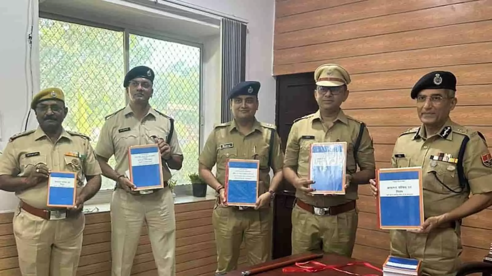 तस्वीर में पांच पुलिस अधिकारी नीले रंग की प्रशिक्षण पुस्तकें हाथ में लिए खड़े दिखाई दे रहे हैं। तस्वीर में पांच पुलिस अधिकारी नीले रंग की प्रशिक्षण पुस्तकें हाथ में लिए खड़े दिखाई दे रहे हैं।