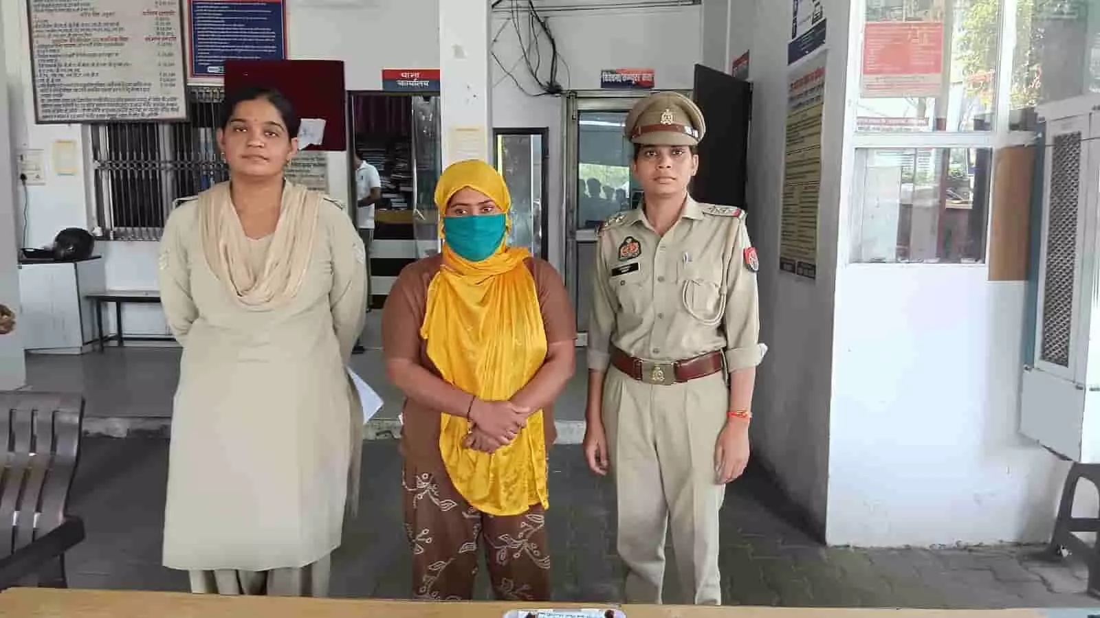 तस्वीर में थाने के अंदर दो महिला पुलिसकर्मियों के बीच खड़ी गिरफ्तार महिला दिखाई दे रही है। तस्वीर में थाने के अंदर दो महिला पुलिसकर्मियों के बीच खड़ी गिरफ्तार महिला दिखाई दे रही है।