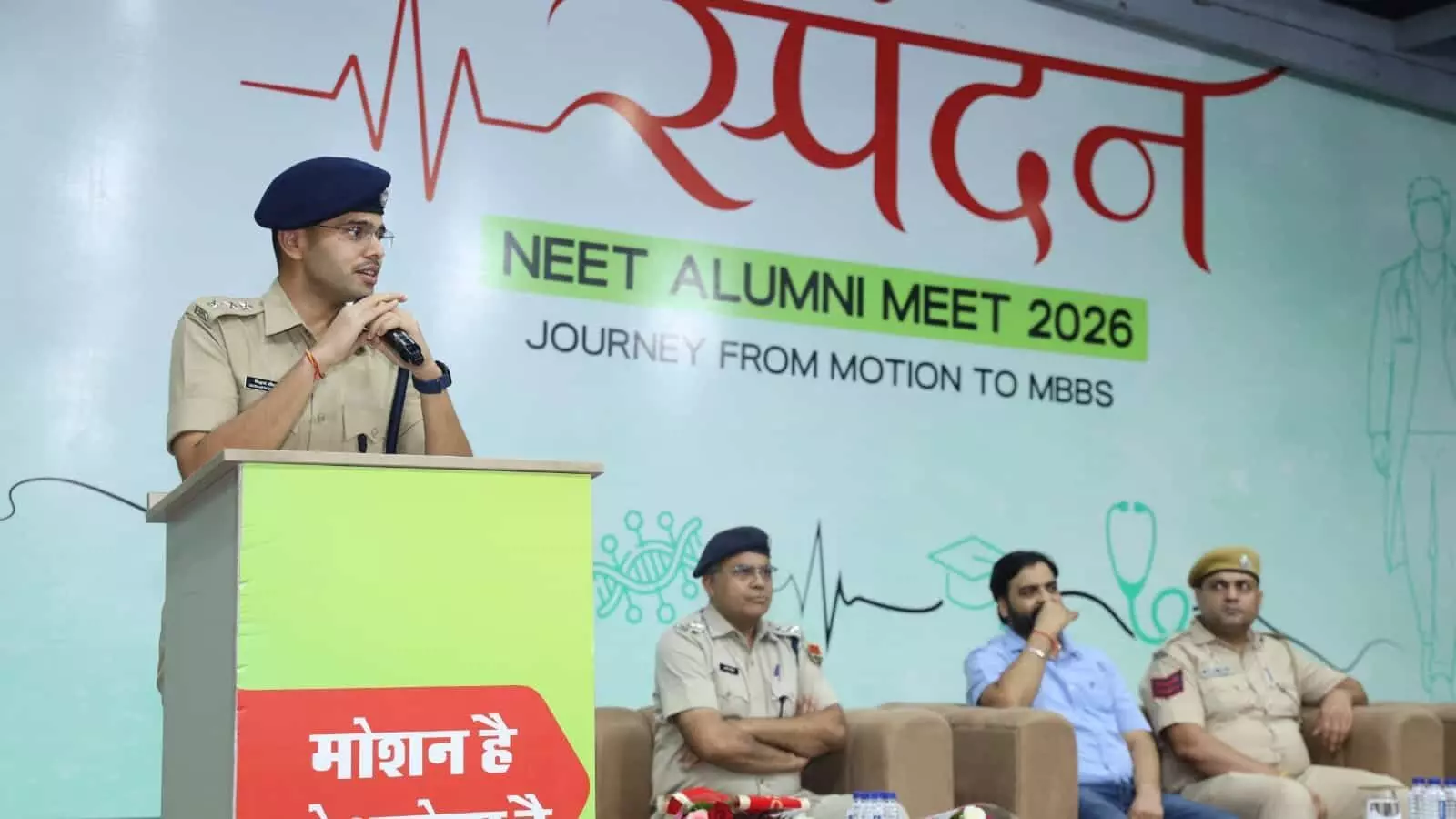 तस्वीर में पुलिस अधिकारी मंच पर खड़े होकर विद्यार्थियों को संबोधित कर रहे हैं और अन्य अधिकारी बैठे हुए हैं। तस्वीर में पुलिस अधिकारी मंच पर खड़े होकर विद्यार्थियों को संबोधित कर रहे हैं और अन्य अधिकारी बैठे हुए हैं।