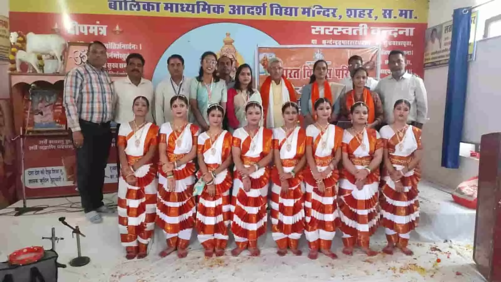 तस्वीर में दिख रही छात्राएं पारंपरिक पोशाक में आयोजकों और अतिथियों के साथ मंच पर खड़ी हैं। तस्वीर में दिख रही छात्राएं पारंपरिक पोशाक में आयोजकों और अतिथियों के साथ मंच पर खड़ी हैं।