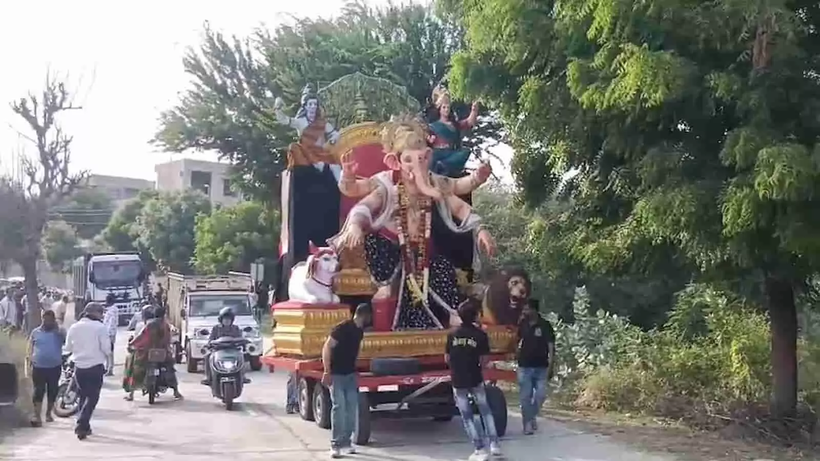 तस्वीर में सड़क पर गणेश प्रतिमा ले जाते लोग और वाहन नजर आ रहे हैं। तस्वीर में सड़क पर गणेश प्रतिमा ले जाते लोग और वाहन नजर आ रहे हैं।