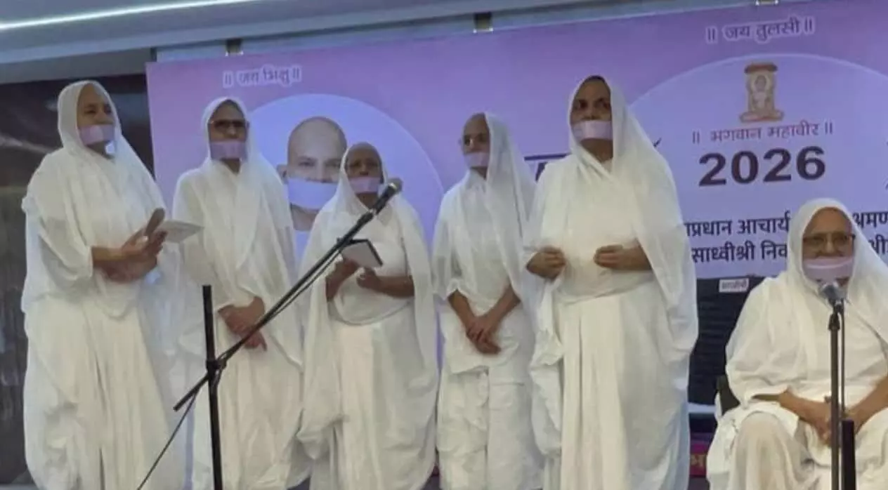 तस्वीर में मंच पर खड़े होकर श्वेत वस्त्र और मुखपट्ट पहने साध्वीवृंद भक्ति गीत की प्रस्तुति दे रही हैं और एक साध्वी दाईं ओर बैठी हैं. तस्वीर में मंच पर खड़े होकर श्वेत वस्त्र और मुखपट्ट पहने साध्वीवृंद भक्ति गीत की प्रस्तुति दे रही हैं और एक साध्वी दाईं ओर बैठी हैं.