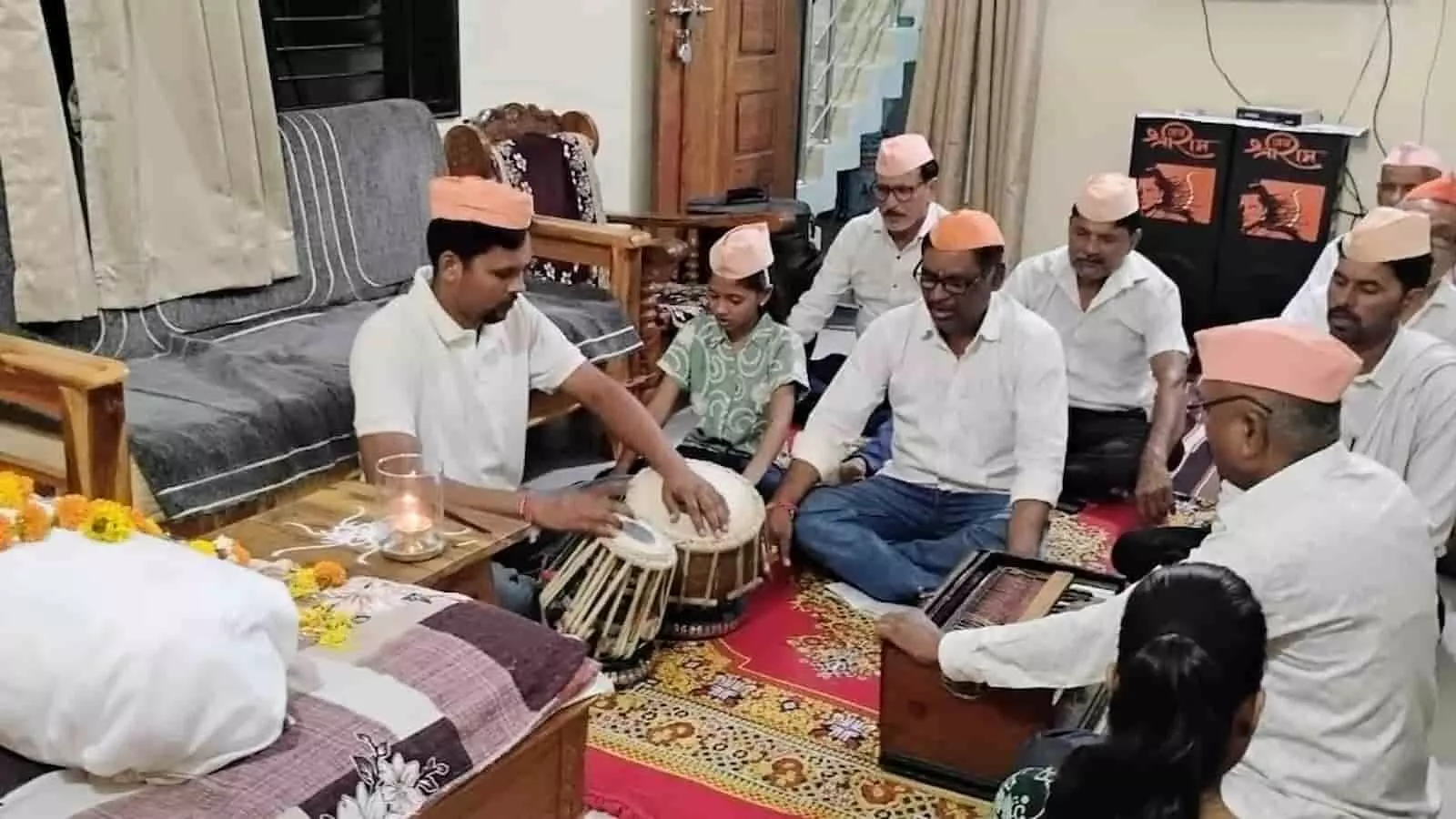 तस्वीर में एक घर के भीतर फर्श पर बैठकर ढोलक और हारमोनियम के साथ राष्ट्रसंत तुकडोजी महाराज की सामुदायिक प्रार्थना करते हुए लोग दिखाई दे रहे हैं। तस्वीर में एक घर के भीतर फर्श पर बैठकर ढोलक और हारमोनियम के साथ राष्ट्रसंत तुकडोजी महाराज की सामुदायिक प्रार्थना करते हुए लोग दिखाई दे रहे हैं।