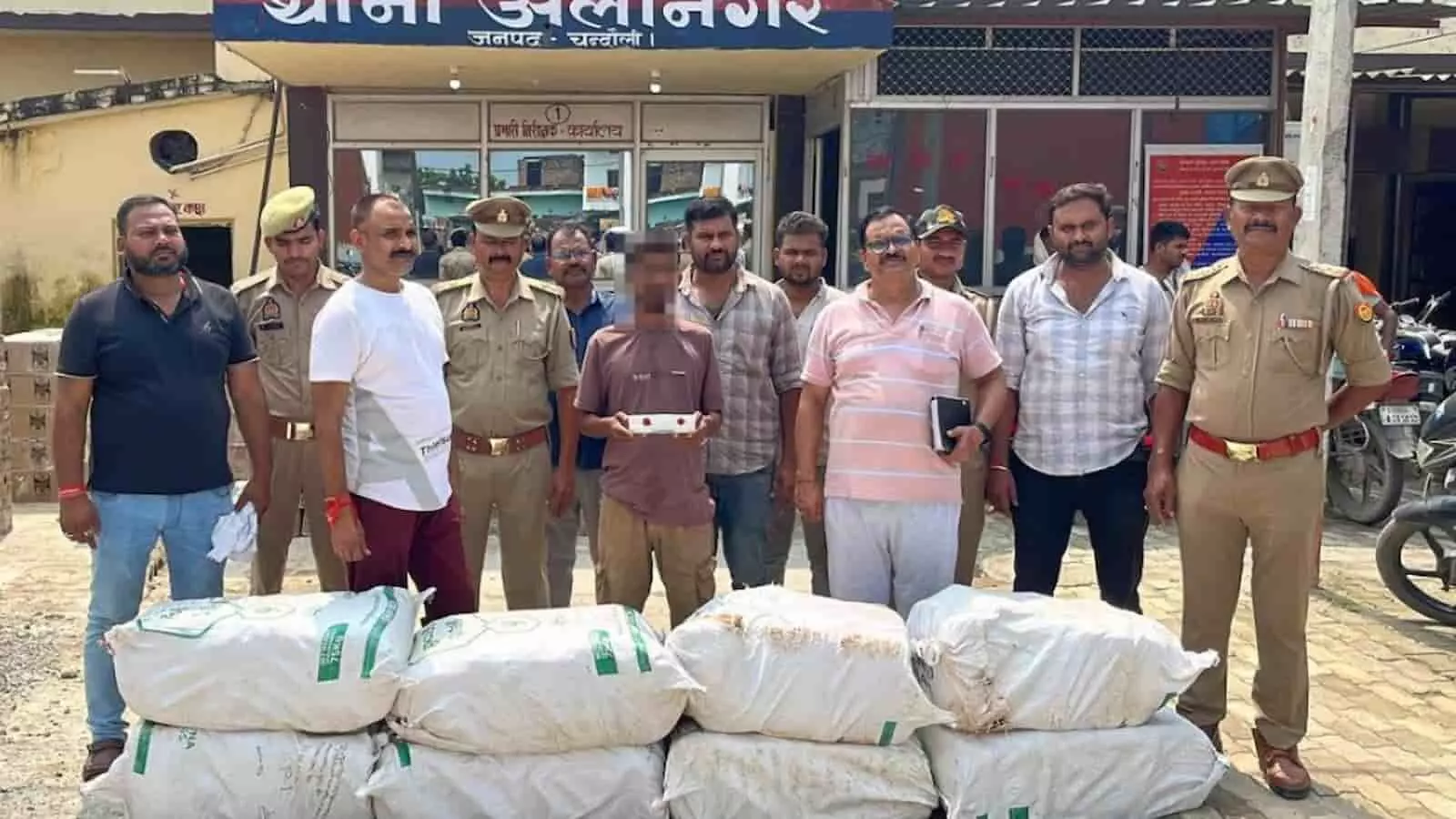 तस्वीर में थाना अलीनगर के सामने खड़े पुलिसकर्मियों और सादे कपड़ों में मौजूद लोगों के बीच में एक गिरफ्तार व्यक्ति और आगे रखी सफेद बोरियों में भरा गांजा दिखाई दे रहा है। तस्वीर में थाना अलीनगर के सामने खड़े पुलिसकर्मियों और सादे कपड़ों में मौजूद लोगों के बीच में एक गिरफ्तार व्यक्ति और आगे रखी सफेद बोरियों में भरा गांजा दिखाई दे रहा है।
