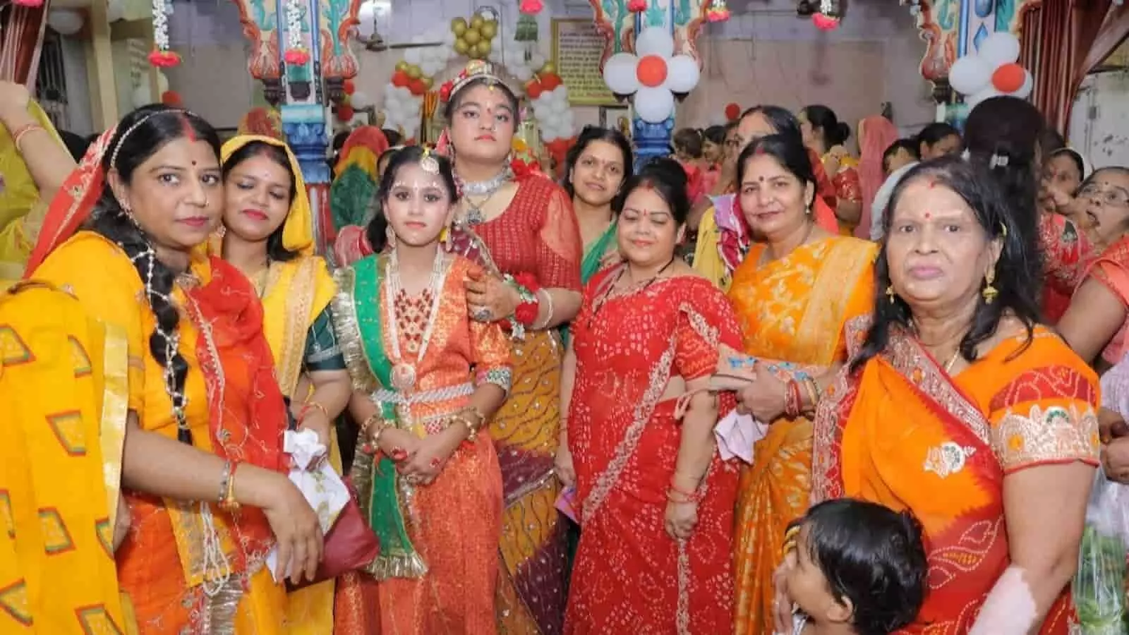 तस्वीर में पारंपरिक वेशभूषा और आभूषणों में सजी बालिका और महिलाएं मंदिर परिसर में खड़ी हैं। तस्वीर में पारंपरिक वेशभूषा और आभूषणों में सजी बालिका और महिलाएं मंदिर परिसर में खड़ी हैं।